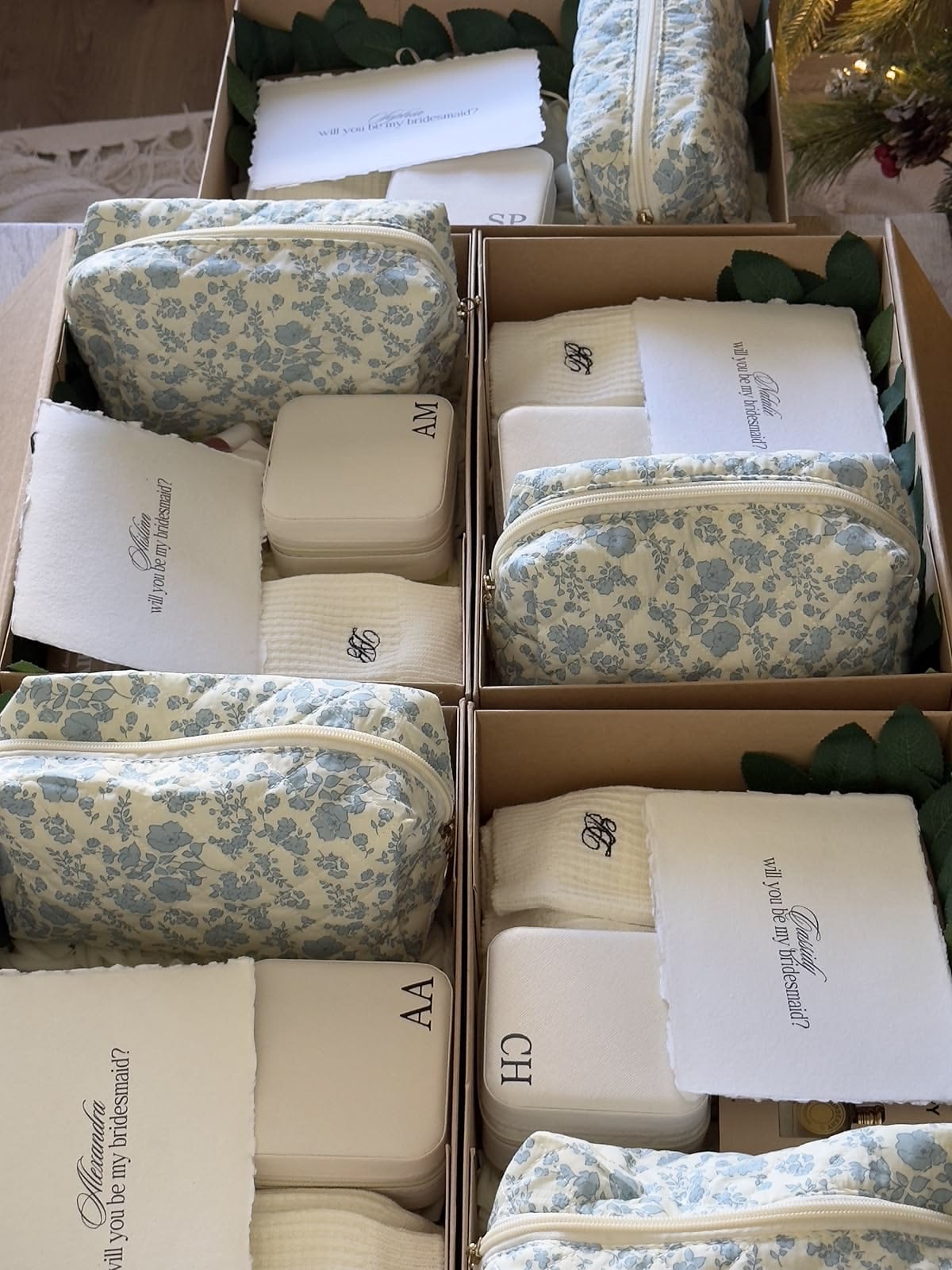 A row of bridesmaid proposal boxes, each with a floral pouch, monogrammed jewellery case and a handwritten card