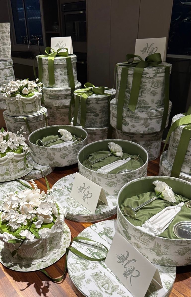 Toile-wrapped hat boxes tied with green ribbon, filled with folded robes and flowers